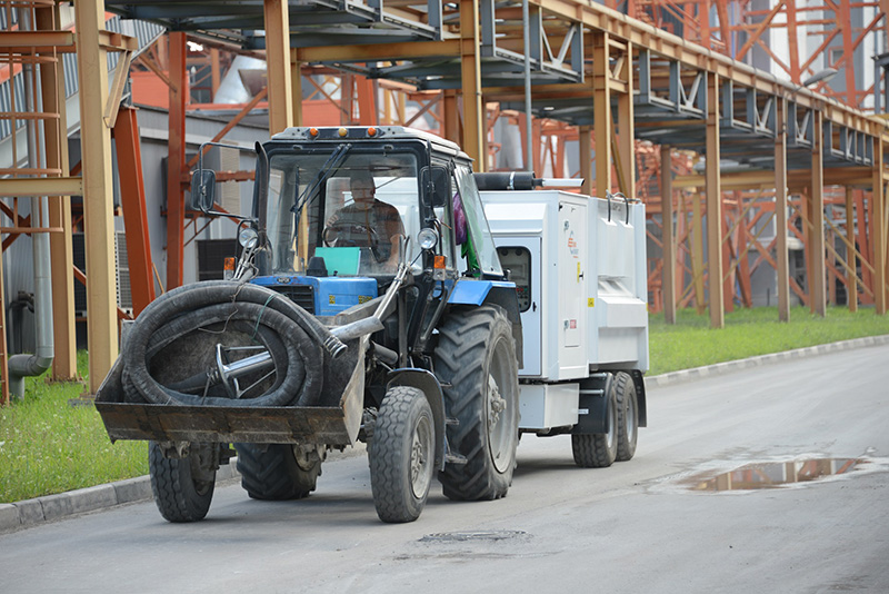 DISAB TrailerVAC SET-10T unit mounted on a trailer and towed by a tractor through an industrial facility, illustrating its mobility and suitability for cleaning tasks across large-scale production environments.