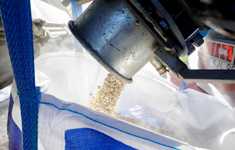 Close-up of industrial vacuum hose from a DISAB unit transferring granular material into a blue-lined big bag, illustrating precise and dust-controlled material handling in heavy industry.