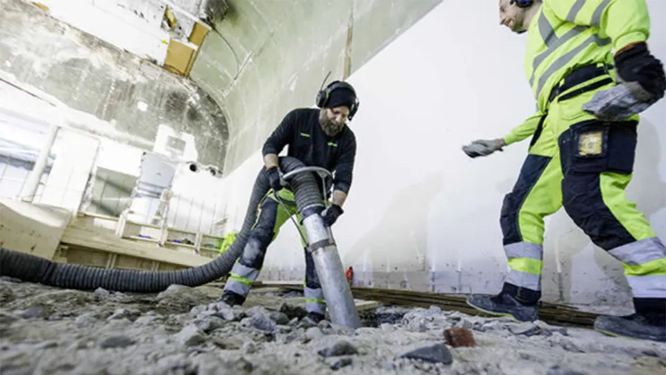 Industrial operator uses a DISAB vacuum loader to remove wet debris from the ground during a heavy-duty cleaning operation.
