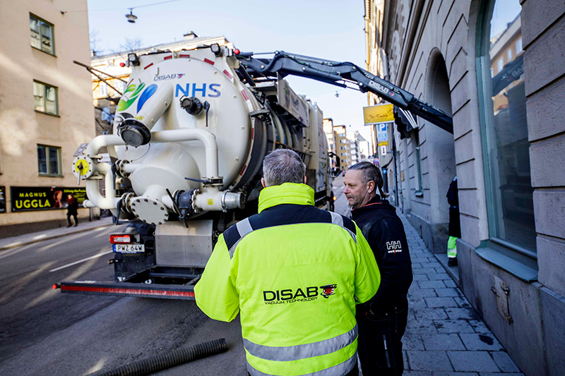 DISAB technician training an operator to safely use a vacuum loader on a city street